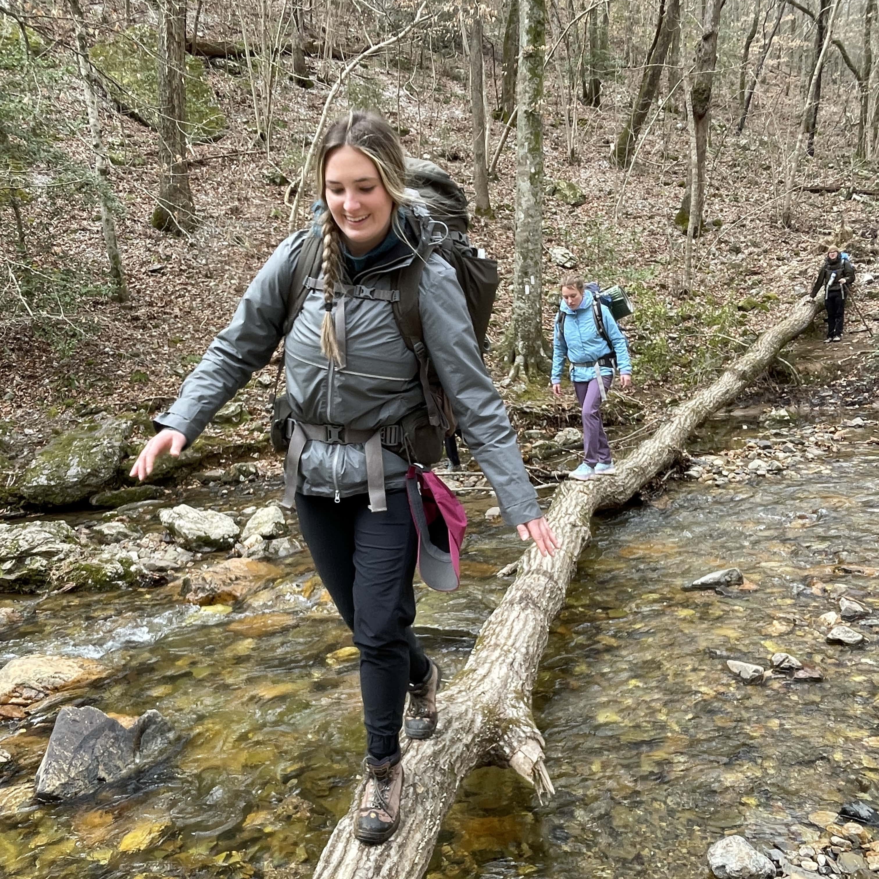 Student walking over fallen tree branch