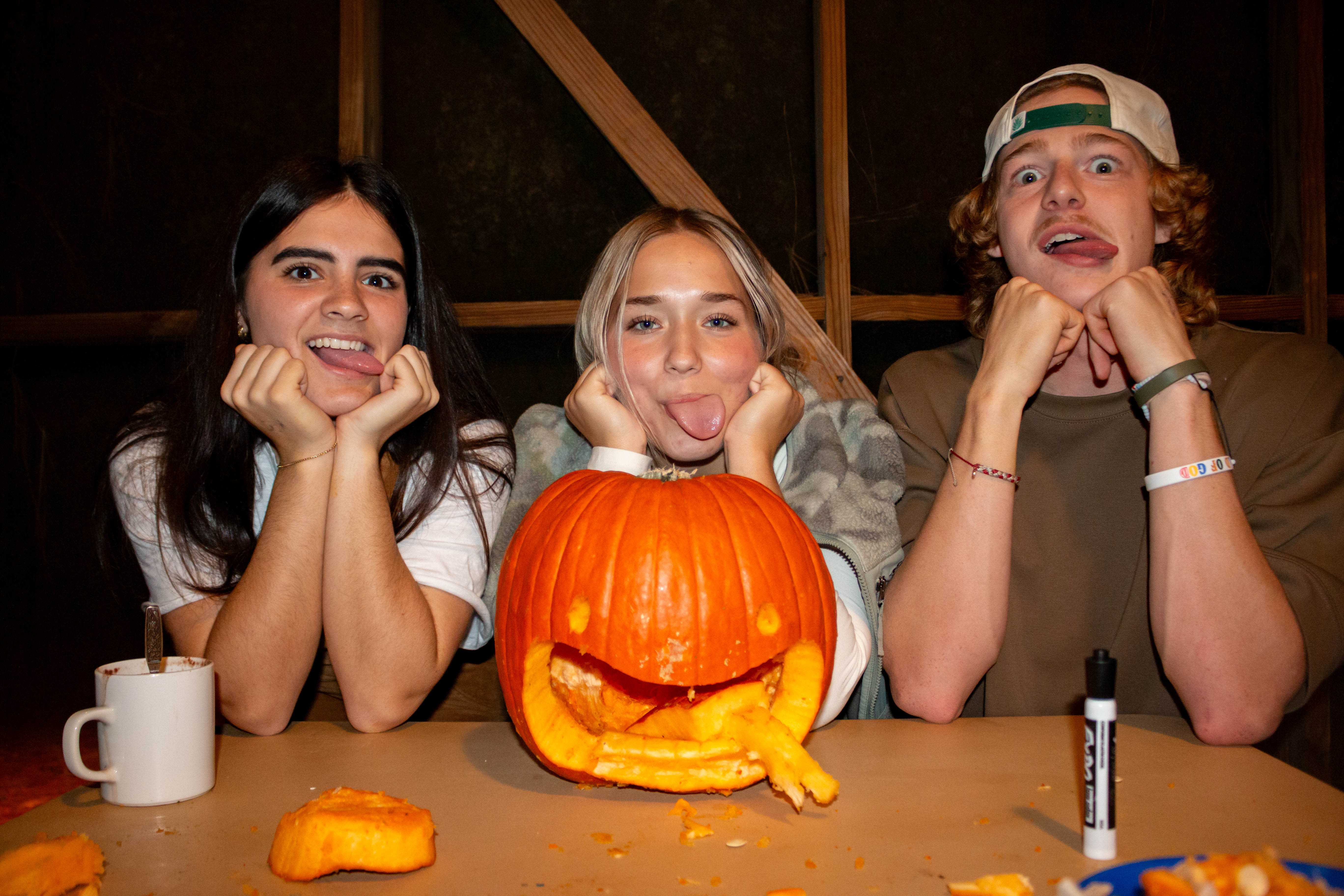 Students posing in front of carved pumpkin